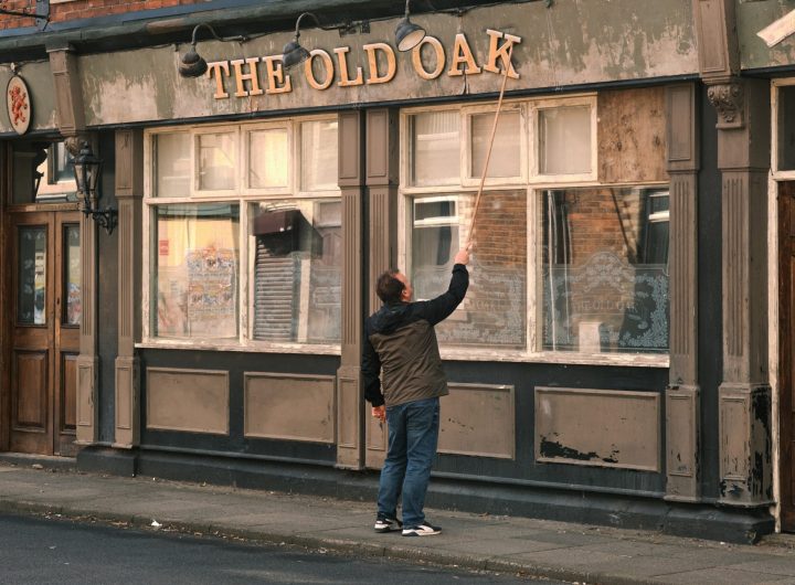 Fotograma de The old oak, donde un hombre arregla el letrero de un bar, al que se le ha caído una letra.
